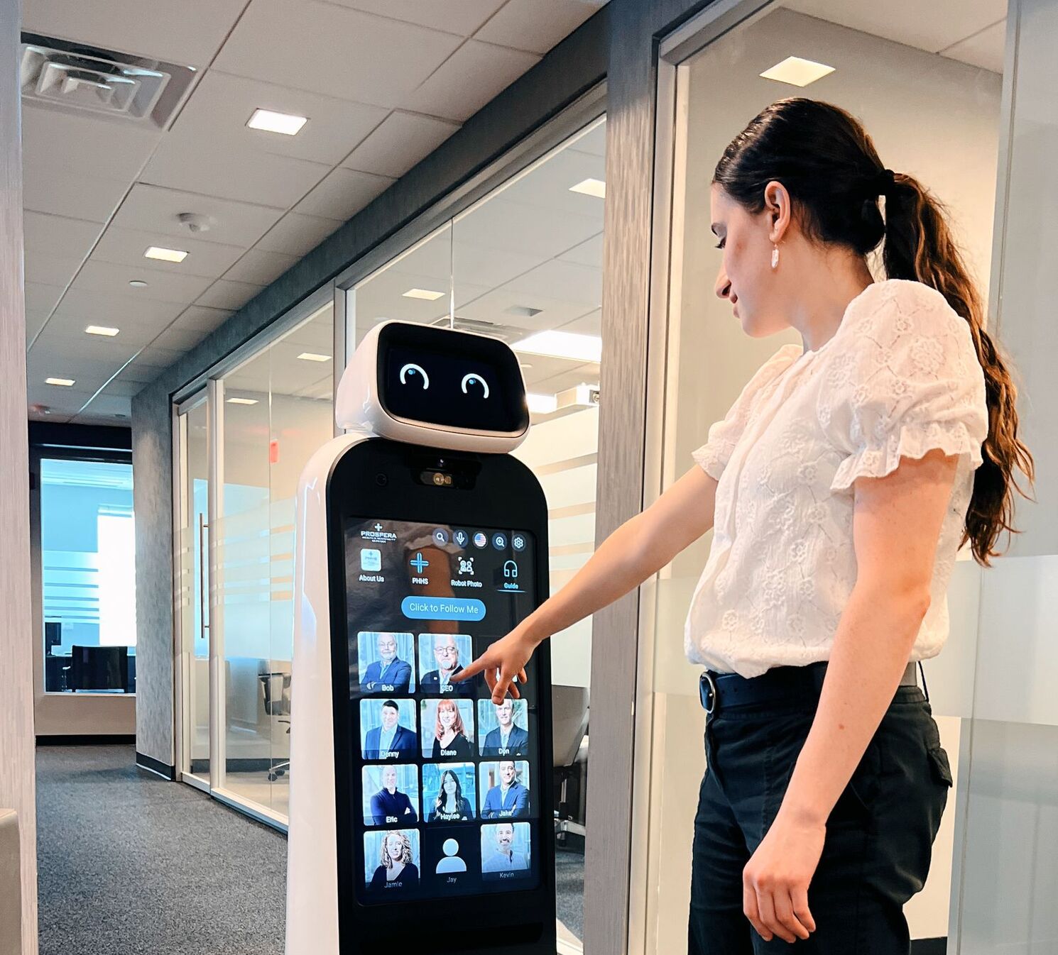 Lady pressing the touchscreen on a guide robot