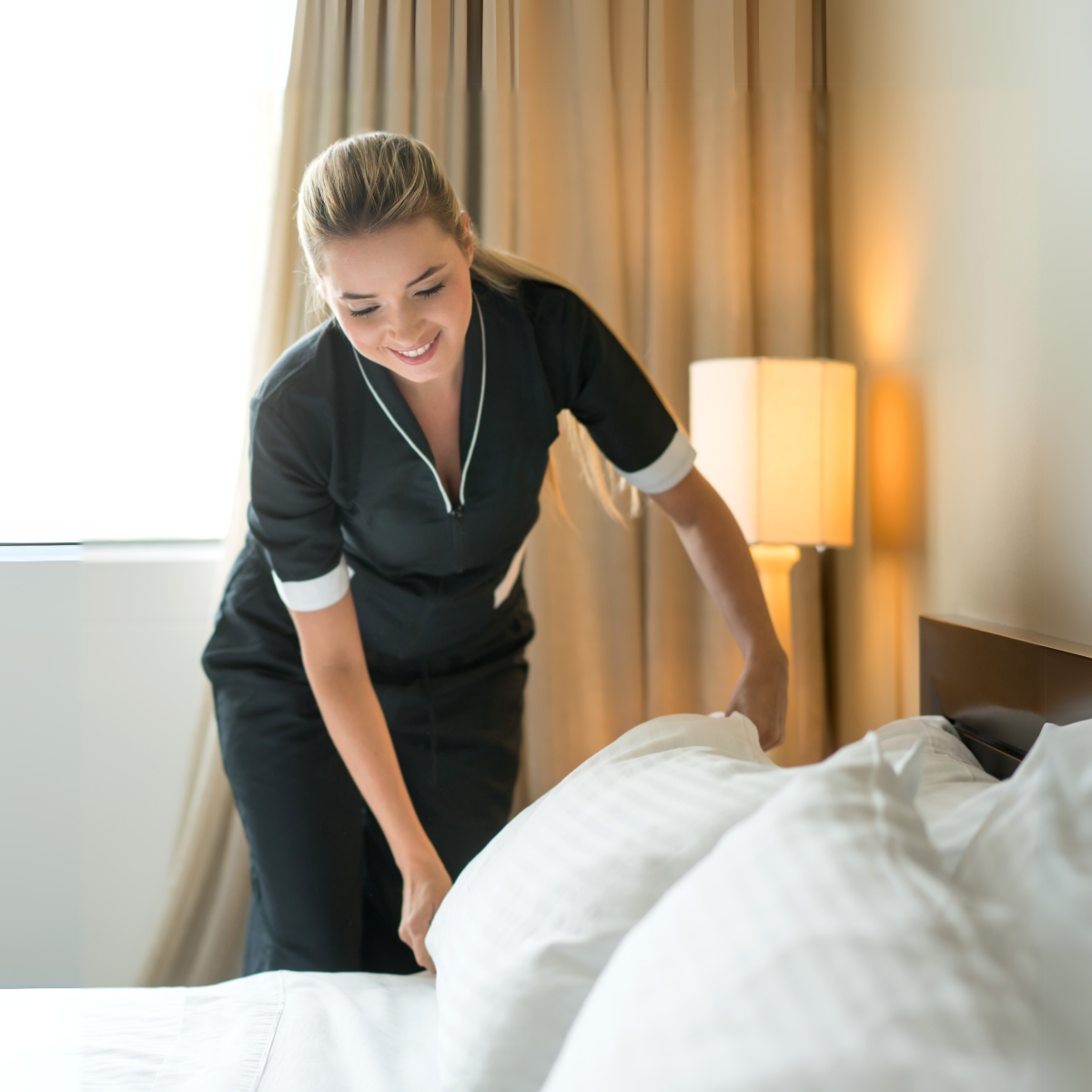 Housekeeper making hotel bed